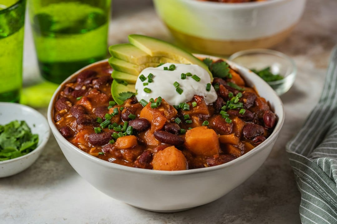 Kid-Friendly Crock Pot Meals: 10 Easy Slow Cooker Dinners 3 Mild slow-cooker bean and sweet potato chili with avocado served family style
