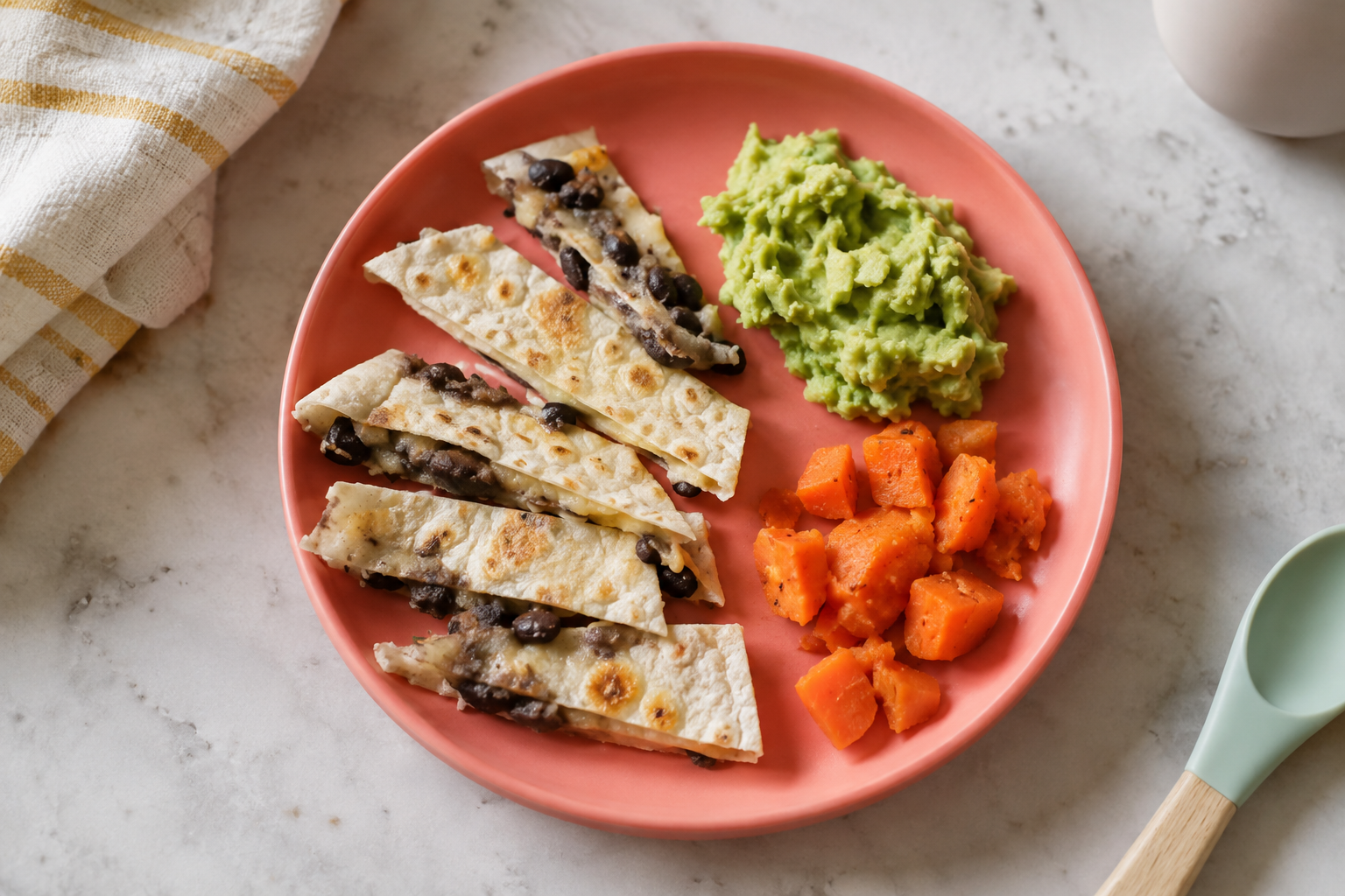 Soft bean and cheese quesadilla strips with mashed avocado and cooked carrots.